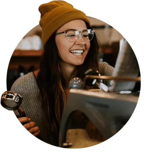 Woman smiling while making coffee in a cafe setting.